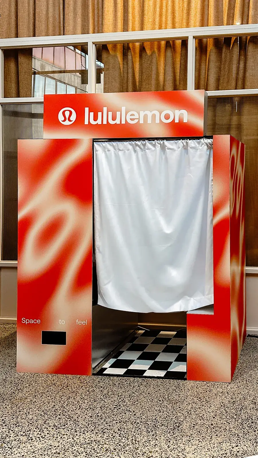 Booth wrapped in red lululemon campaign artwork inside a store